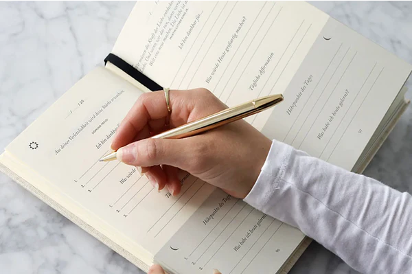 Writing in the journal with a gold pen