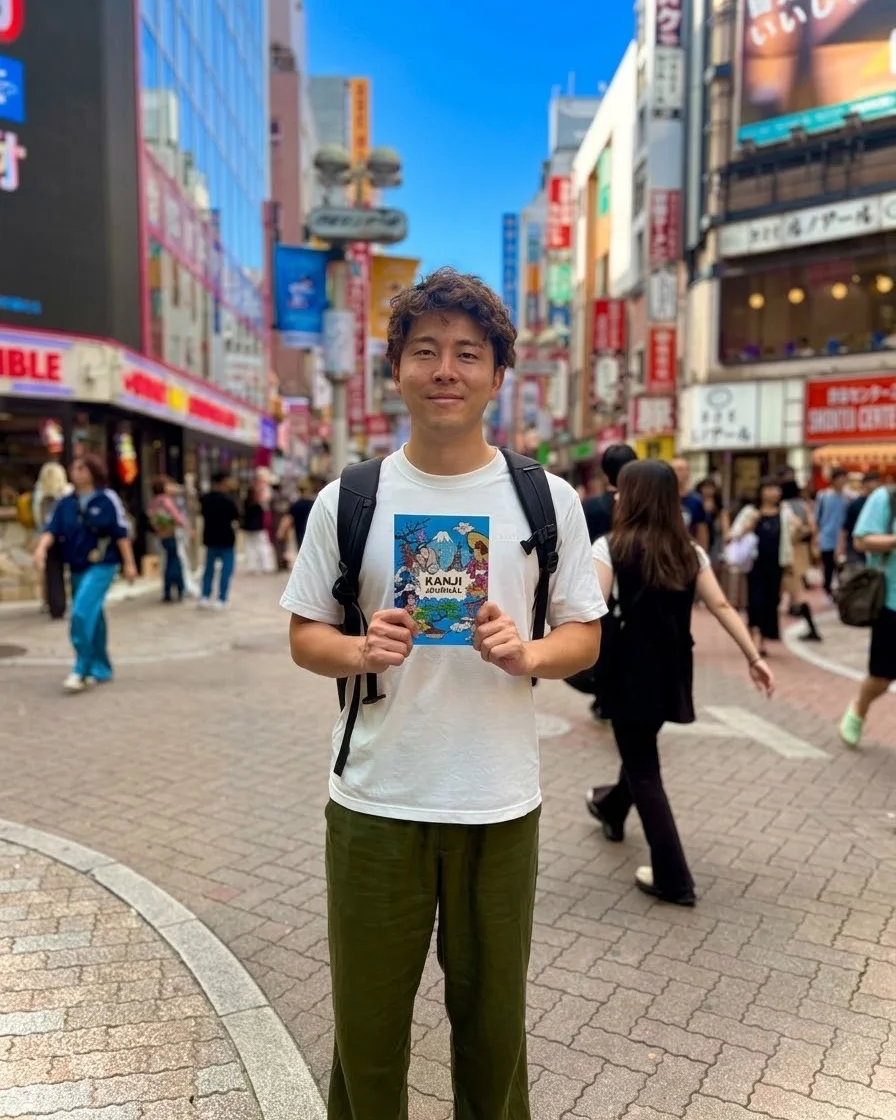 Holding up KANJI JOURNAL on a busy Tokyo street